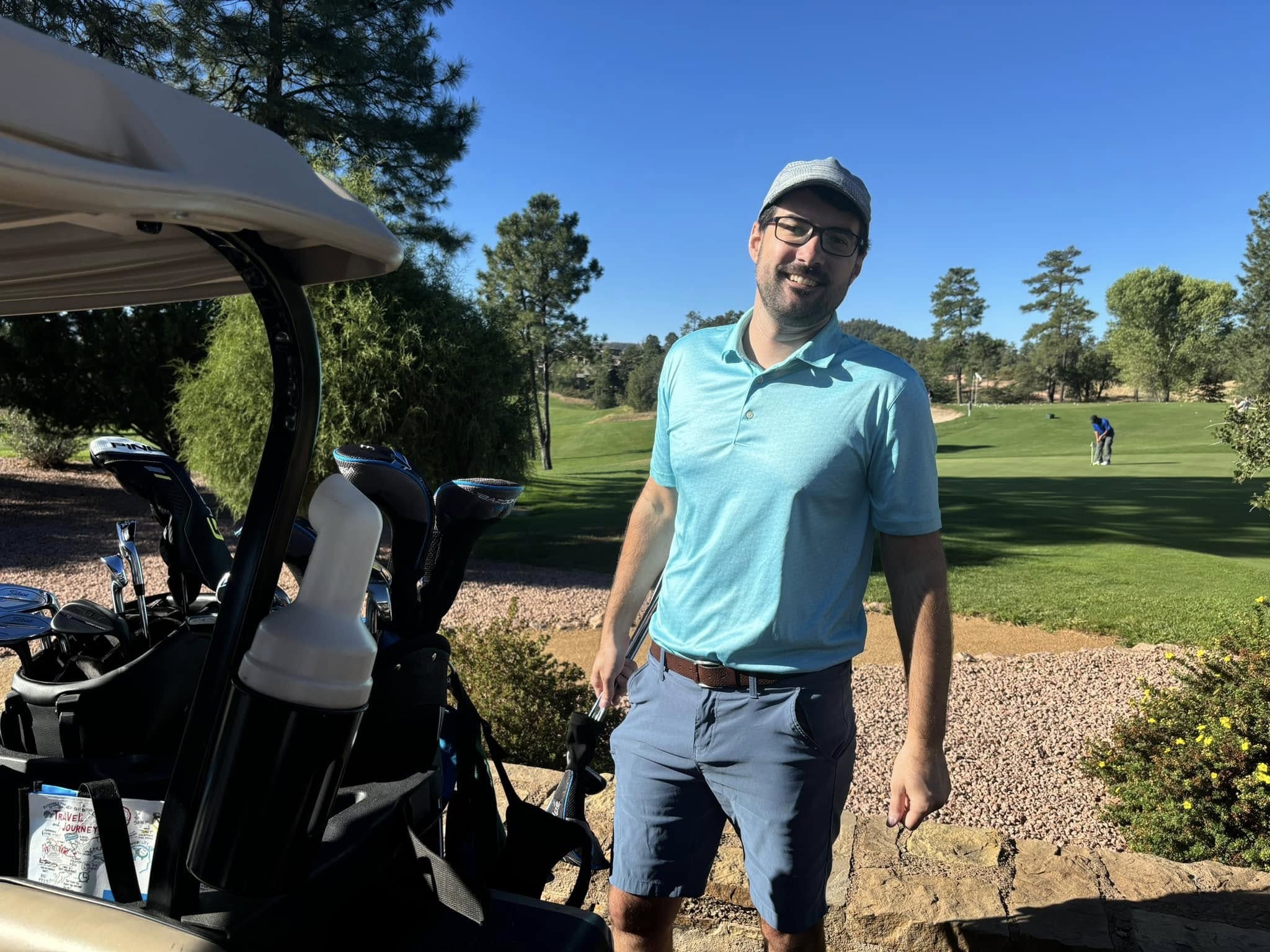 A tournament golfer standing beside his golf cart on the course