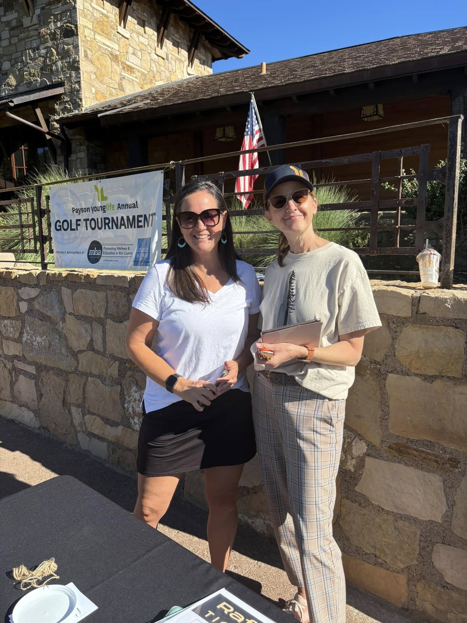 Two tournament volunteers welcoming guests outside the clubhouse