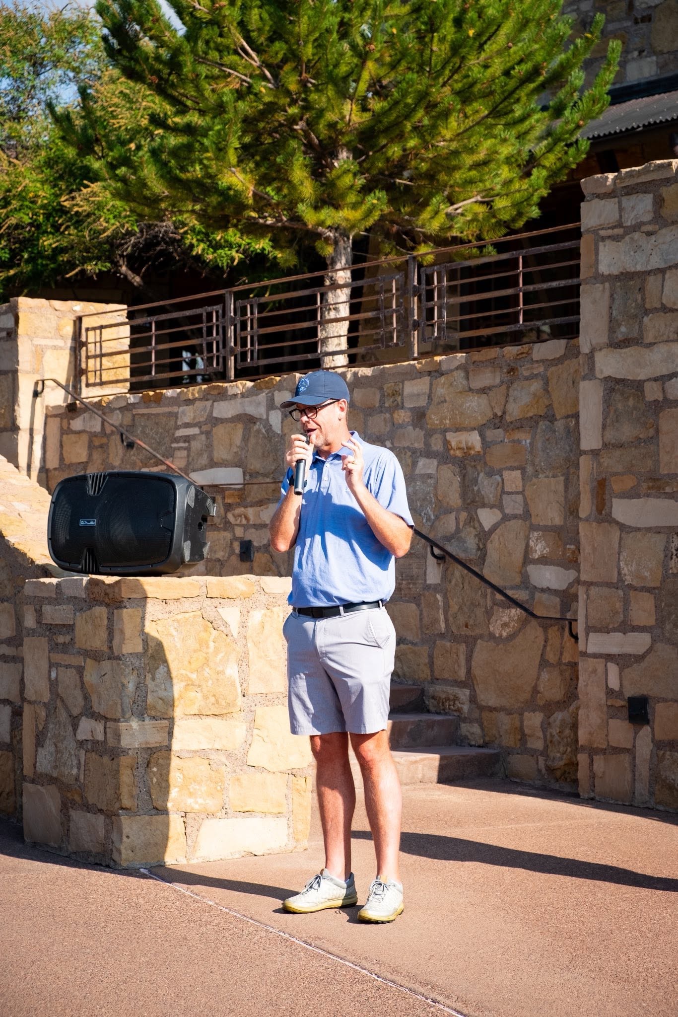 A tournament organizer welcoming guests with remarks outside the clubhouse